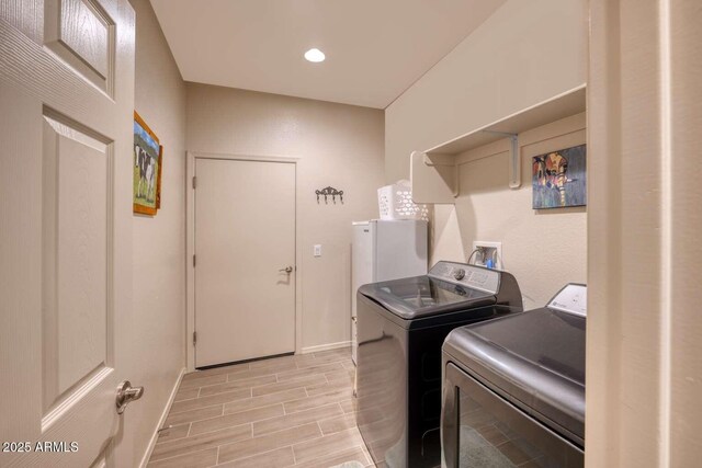 laundry area with recessed lighting, wood tiled floor, laundry area, independent washer and dryer, and baseboards