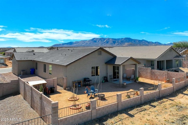 back of house featuring a patio, a fenced backyard, a mountain view, a tiled roof, and stucco siding