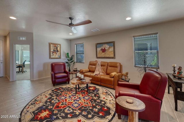 living area with a textured ceiling, ceiling fan, and visible vents