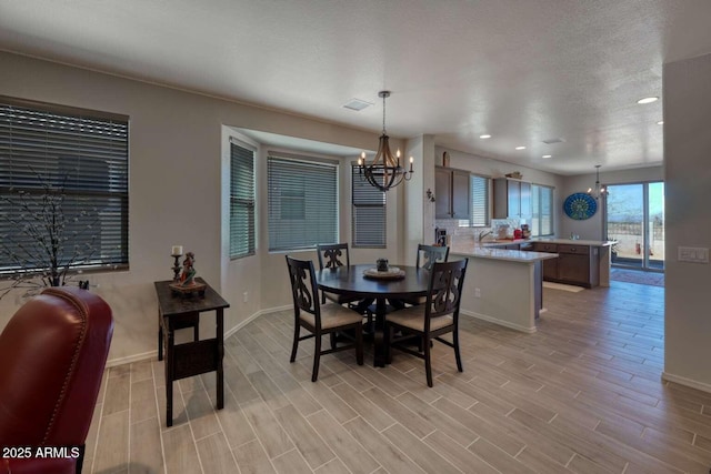 dining area featuring an inviting chandelier, visible vents, baseboards, and wood finish floors