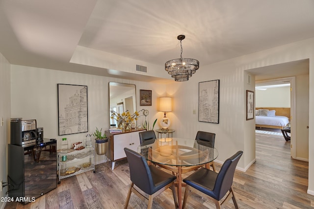 dining area with wood-type flooring and a chandelier