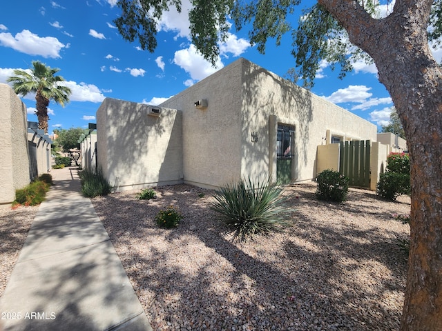 view of side of property with fence and stucco siding