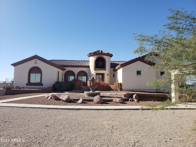 mediterranean / spanish house featuring a tile roof and stucco siding