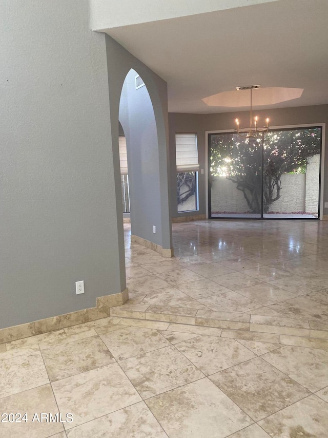 tiled empty room featuring a notable chandelier