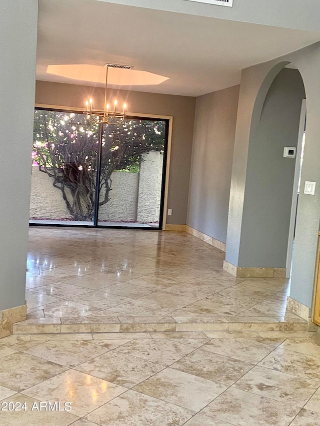 empty room featuring an inviting chandelier and tile floors