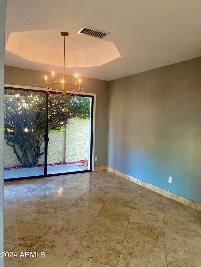 empty room featuring an inviting chandelier, a tray ceiling, and tile floors