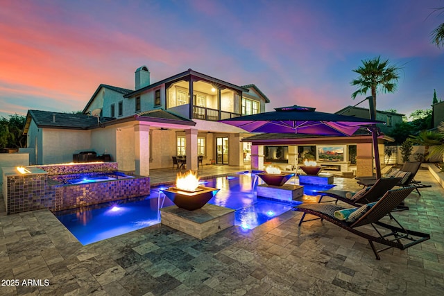 20866 W Werner Pl, Buckeye, AZ 85396 - back of house at dusk featuring a fire pit, a patio area, a balcony, an outdoor bar, and a chimney