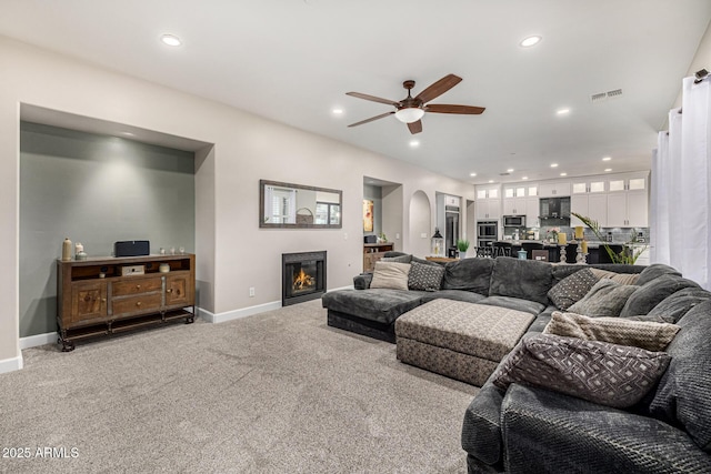 20866 W Werner Pl, Buckeye, AZ 85396 - carpeted living room with a ceiling fan, recessed lighting, baseboards, a glass covered fireplace, and arched walkways