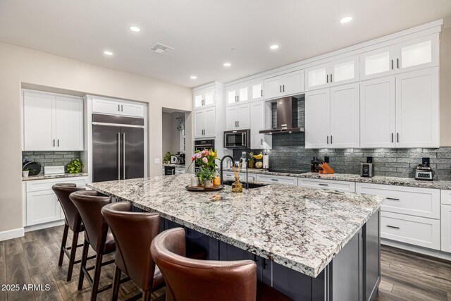20866 W Werner Pl, Buckeye, AZ 85396 - kitchen featuring built in fridge, a sink, stainless steel microwave, backsplash, and wall chimney exhaust hood