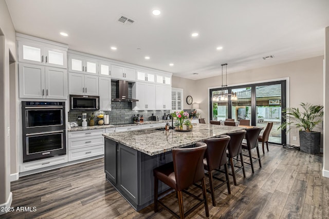 20866 W Werner Pl, Buckeye, AZ 85396 - kitchen with black appliances, wall chimney exhaust hood, dark wood-type flooring, white cabinets, and recessed lighting