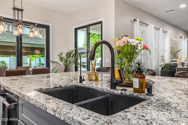20866 W Werner Pl, Buckeye, AZ 85396 - kitchen featuring a sink, light stone counters, open floor plan, pendant lighting, and gray cabinets