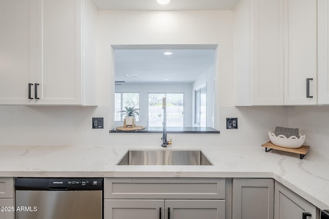 kitchen with a sink, light stone countertops, stainless steel dishwasher, and white cabinetry