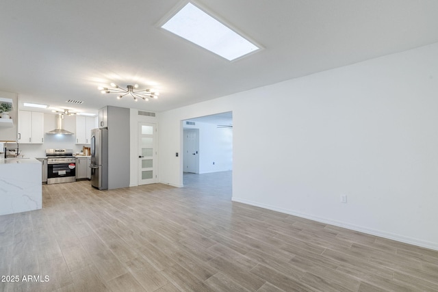 unfurnished living room featuring a sink, visible vents, baseboards, and light wood-style floors