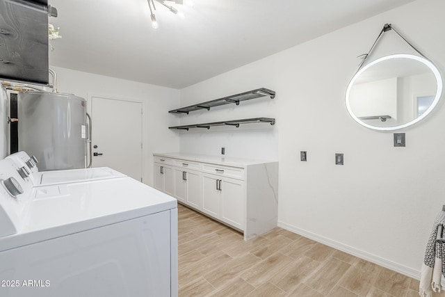 washroom featuring wood finish floors, washer and dryer, water heater, cabinet space, and baseboards