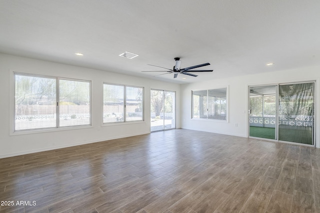 empty room with visible vents, plenty of natural light, baseboards, and wood finished floors