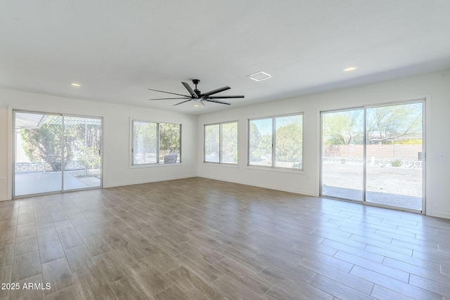 unfurnished living room with visible vents, a healthy amount of sunlight, baseboards, and wood finished floors