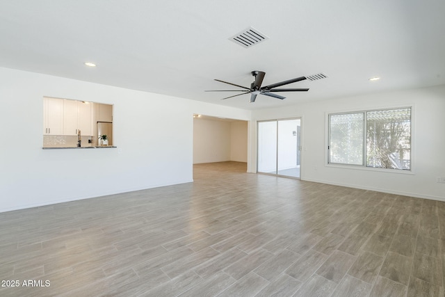 unfurnished living room featuring a ceiling fan, visible vents, baseboards, recessed lighting, and light wood-style floors