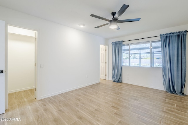 empty room featuring light wood-type flooring, baseboards, and ceiling fan