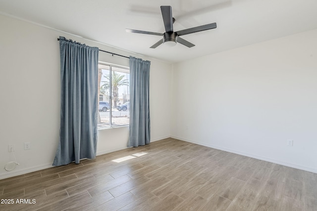 empty room with ceiling fan, baseboards, and wood finished floors