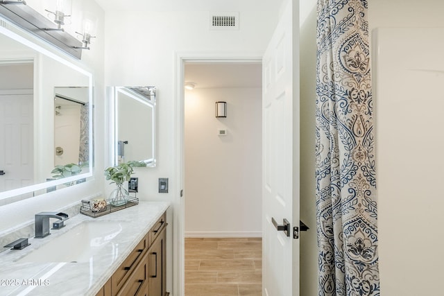 full bathroom with wood finish floors, visible vents, baseboards, and vanity