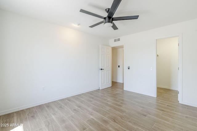 unfurnished bedroom featuring visible vents, a walk in closet, light wood finished floors, baseboards, and ceiling fan