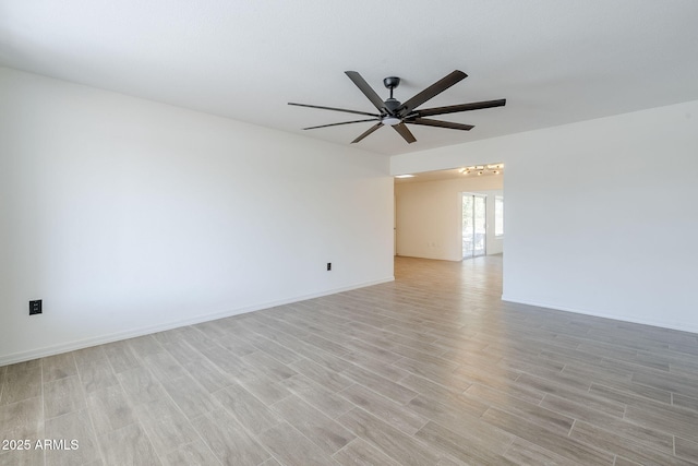 empty room featuring a ceiling fan, light wood-style floors, and baseboards