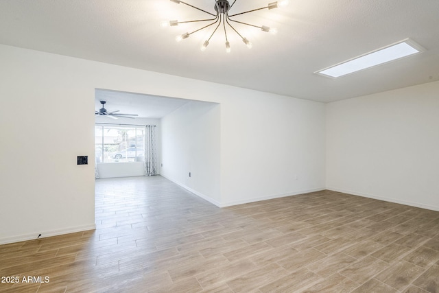 unfurnished room with a notable chandelier, baseboards, and light wood-style floors