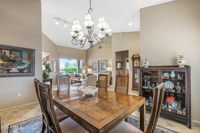 dining room featuring lofted ceiling, light tile patterned floors, track lighting, and an inviting chandelier