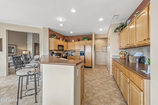 kitchen with light brown cabinetry, a breakfast bar area, tasteful backsplash, kitchen peninsula, and black appliances