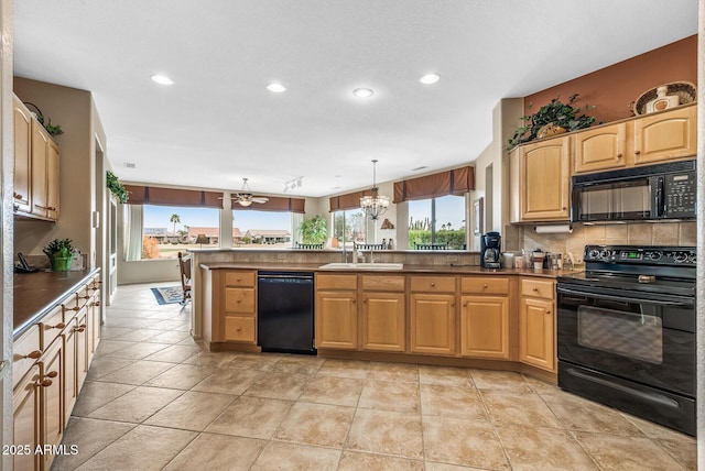 kitchen featuring pendant lighting, a wealth of natural light, sink, and black appliances