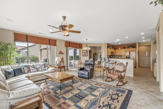 tiled living room with ceiling fan with notable chandelier