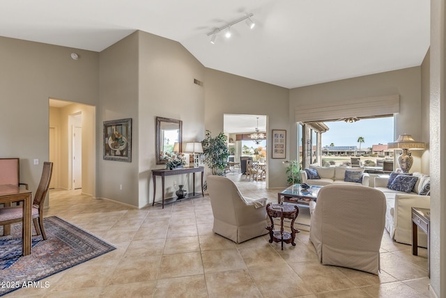 living room featuring light tile patterned floors, vaulted ceiling, and rail lighting