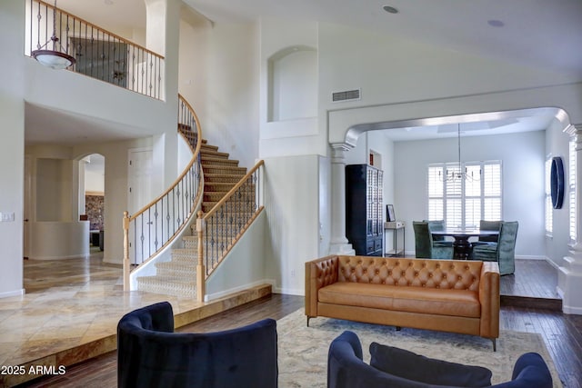 1707 E Carob Dr, Chandler, AZ 85286 - living room featuring arched walkways, a chandelier, ornate columns, a towering ceiling, and baseboards