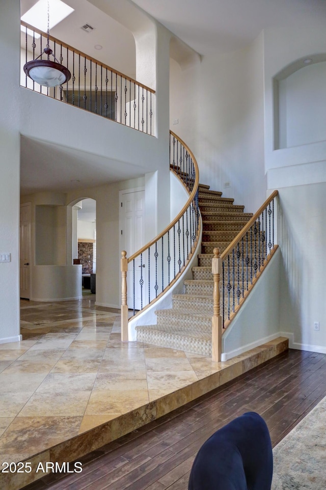 1707 E Carob Dr, Chandler, AZ 85286 - staircase featuring a towering ceiling, wood-type flooring, baseboards, and arched walkways