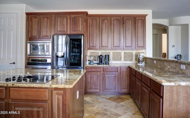 1707 E Carob Dr, Chandler, AZ 85286 - kitchen featuring appliances with stainless steel finishes, arched walkways, decorative backsplash, and light stone countertops