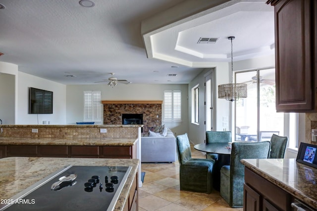1707 E Carob Dr, Chandler, AZ 85286 - kitchen featuring a stone fireplace, ceiling fan, black electric stovetop, and light stone countertops