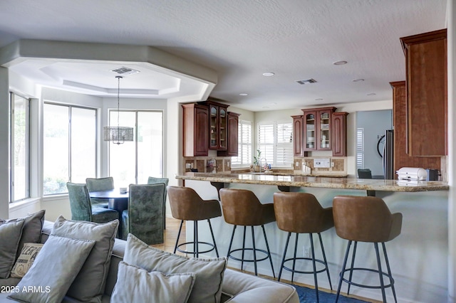 1707 E Carob Dr, Chandler, AZ 85286 - kitchen featuring glass insert cabinets, open floor plan, a kitchen bar, and a textured ceiling