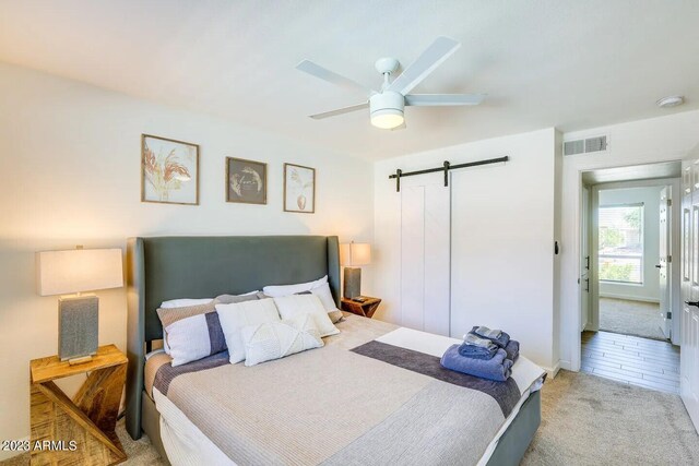 bedroom featuring carpet flooring, a barn door, and ceiling fan