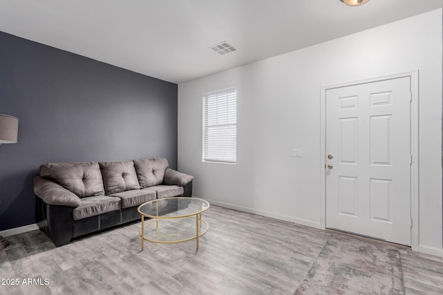 living room with baseboards, visible vents, and wood finished floors