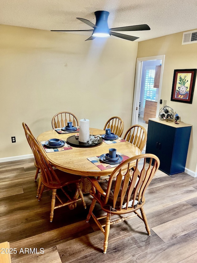 dining room featuring a textured ceiling, ceiling fan, and wood-type flooring