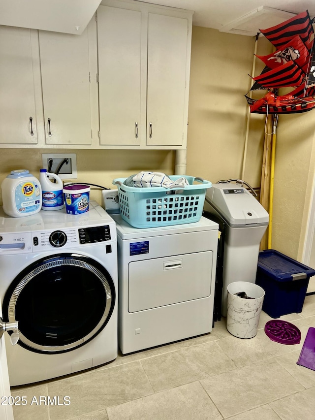 washroom featuring cabinets, washing machine and clothes dryer, and light tile patterned floors