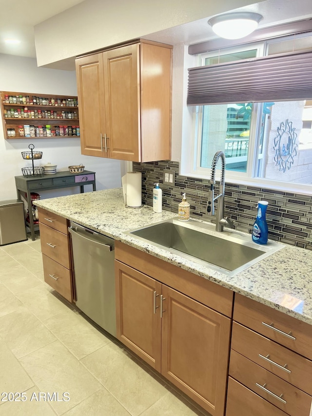 kitchen featuring stainless steel dishwasher, sink, backsplash, and light stone countertops