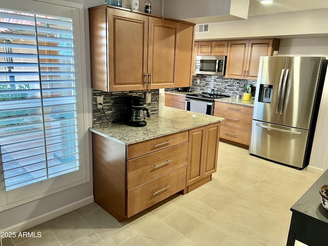 kitchen with light stone countertops, backsplash, and appliances with stainless steel finishes