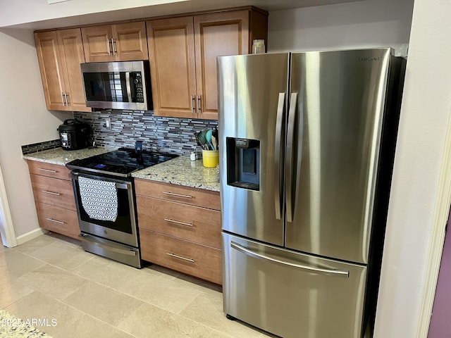 kitchen featuring light stone counters, stainless steel appliances, light tile patterned floors, and tasteful backsplash