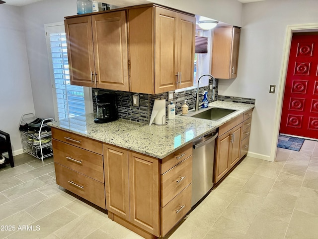 kitchen featuring stainless steel dishwasher, sink, tasteful backsplash, and light stone countertops