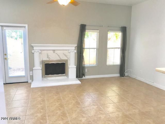 unfurnished living room featuring ceiling fan, a fireplace, and a healthy amount of sunlight