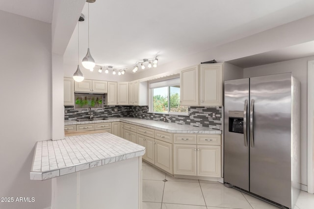 9603 W Calico Dr, Sun City, AZ 85373 - kitchen with stainless steel fridge, backsplash, cream cabinets, pendant lighting, and light tile patterned floors
