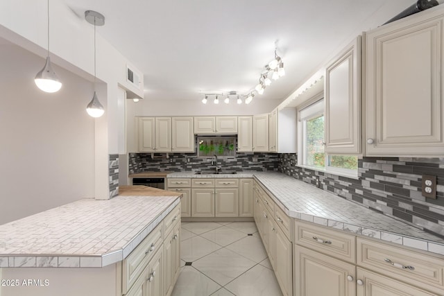 9603 W Calico Dr, Sun City, AZ 85373 - kitchen with cream cabinetry, tasteful backsplash, light countertops, and hanging light fixtures