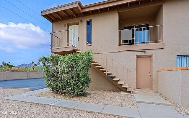 view of front of home featuring stairway, fence, and stucco siding