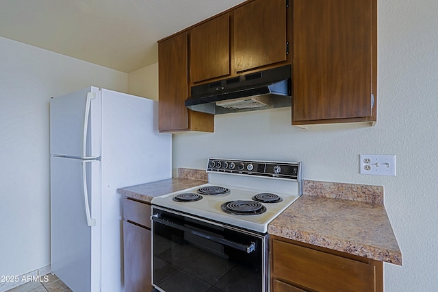 kitchen featuring range with electric cooktop, tile patterned floors, freestanding refrigerator, light countertops, and under cabinet range hood